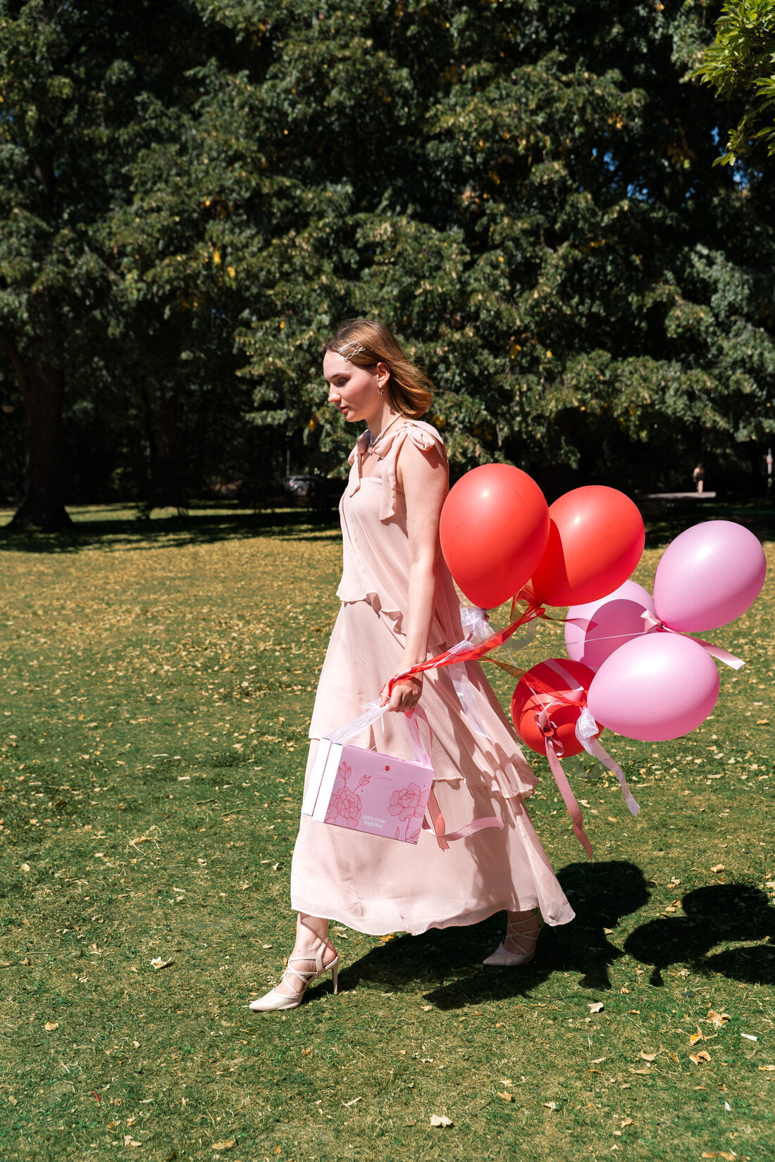 Frau &uuml;berreicht das Love Edition Geschenk mit rosa und roten Ballons